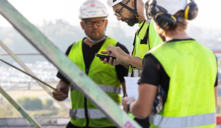 Byggnadsarbetare tittar in i mobilen.